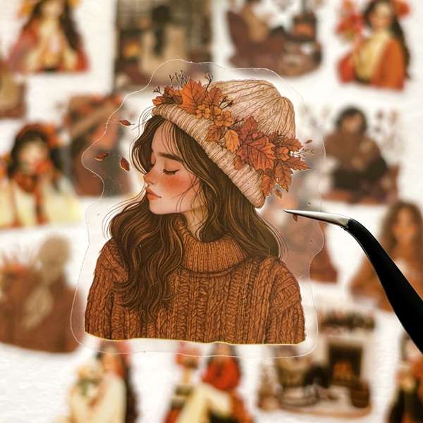 Sticker PET transparent représentant une jeune femme aux cheveux bruns portant un bonnet décoré de feuilles d'automne.